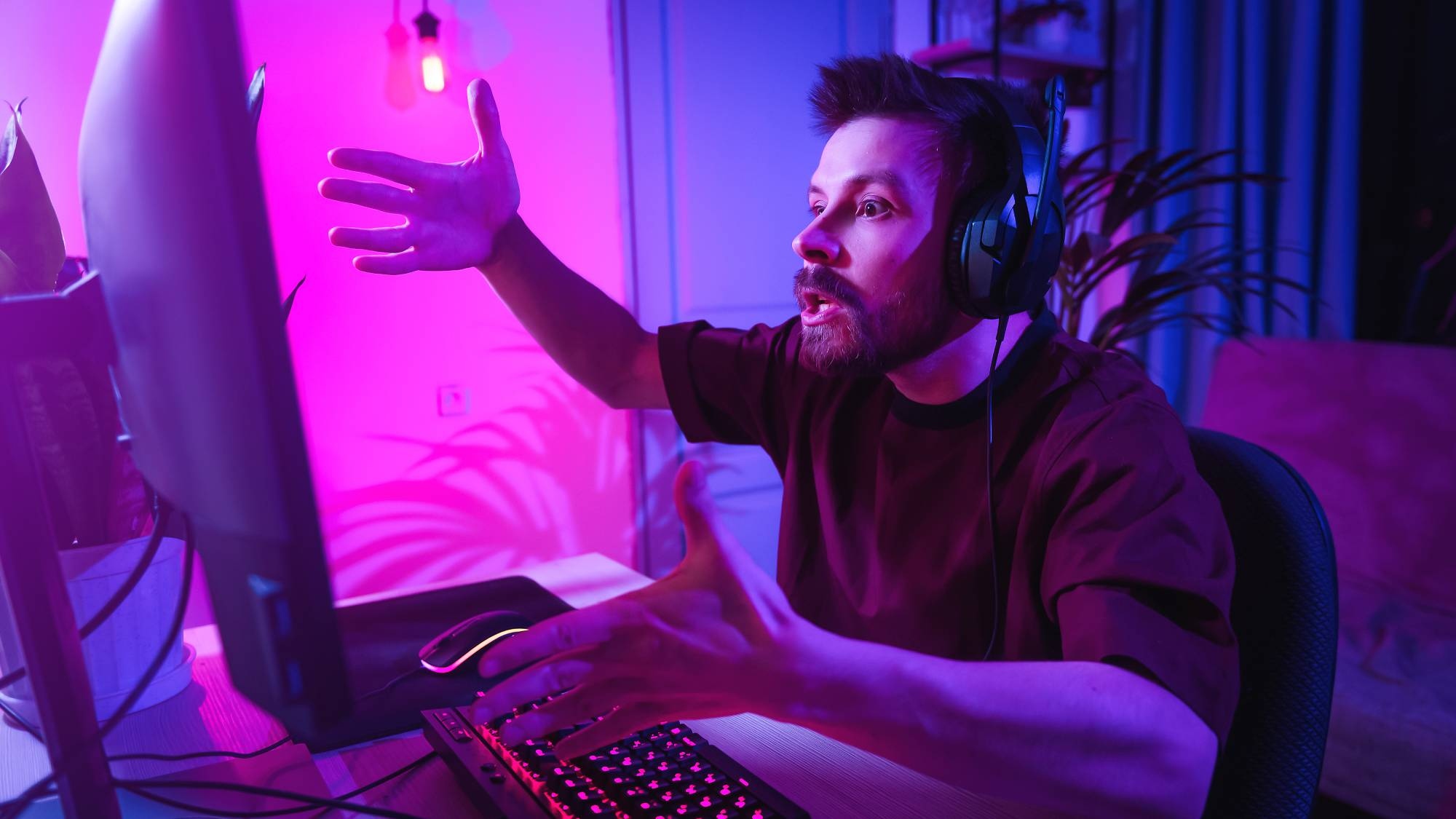 Upset young gamer gesturing at PC monitor in frustration